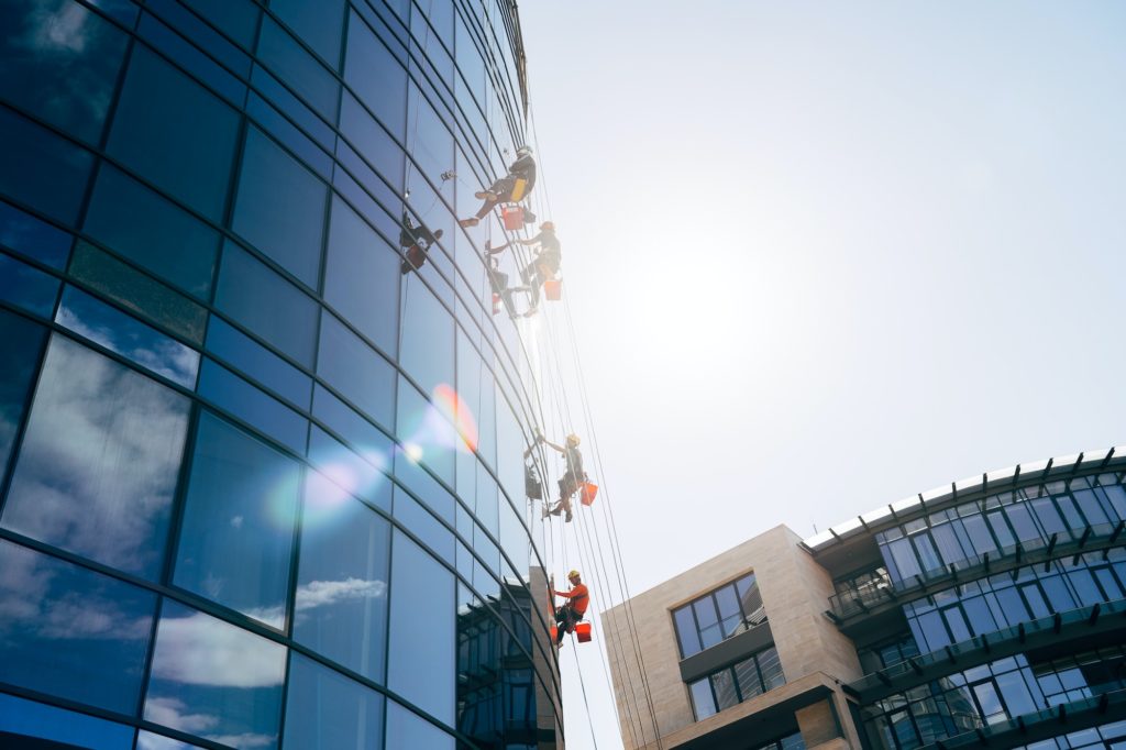 Climbers clean windows from the outside of the building washing the glazing of the facade of a multi